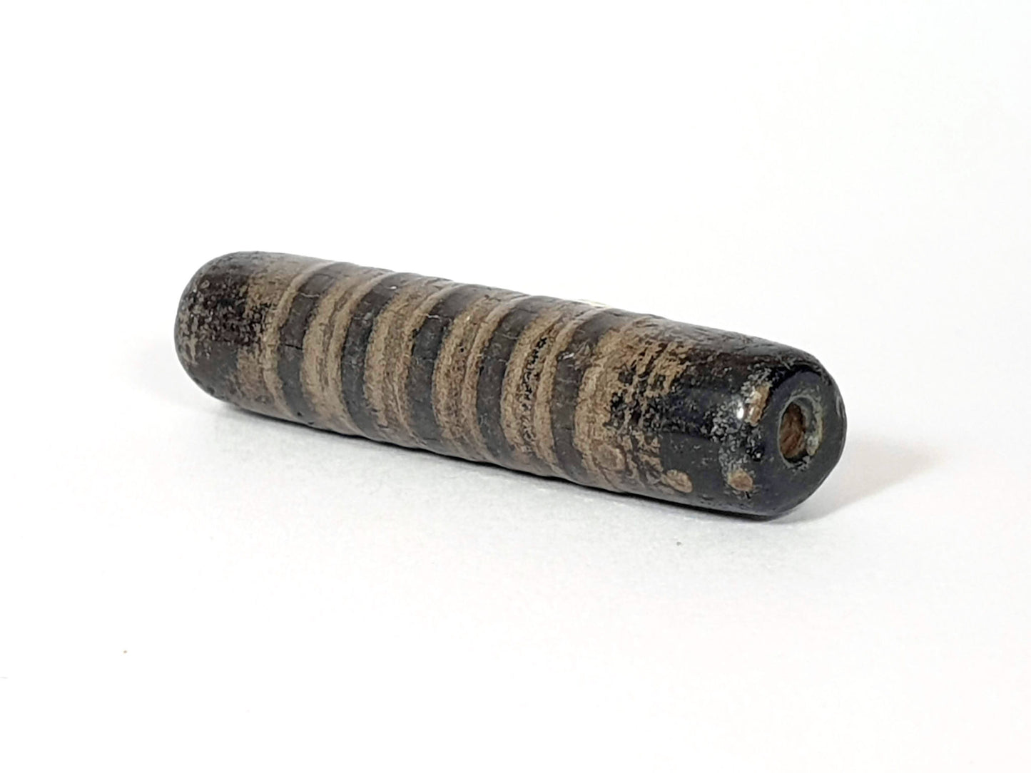 Ac-080420-19SChung, Bead B right end, large drill hole with reddish-brown interior, encrusted dark end cap, unretouched