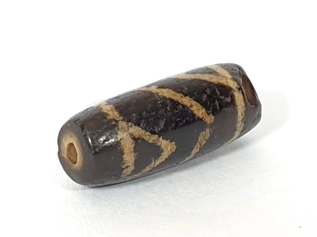 Ancient carnelian dzi bead, tiger tooth motif, dark brown etched agate, cream geometric pattern, visible drill hole, aged patina