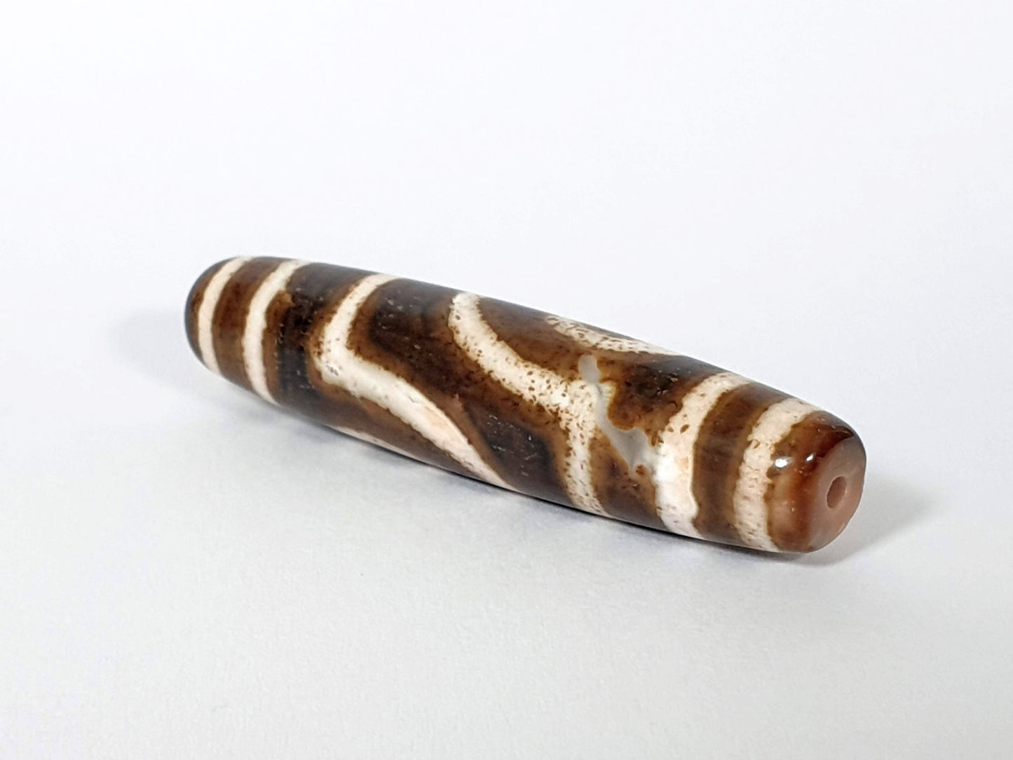Qing Dynasty two eye dzi — angled end, drill hole at warm brown rounded right tip, wave pattern on body, At-0426-2EQ
