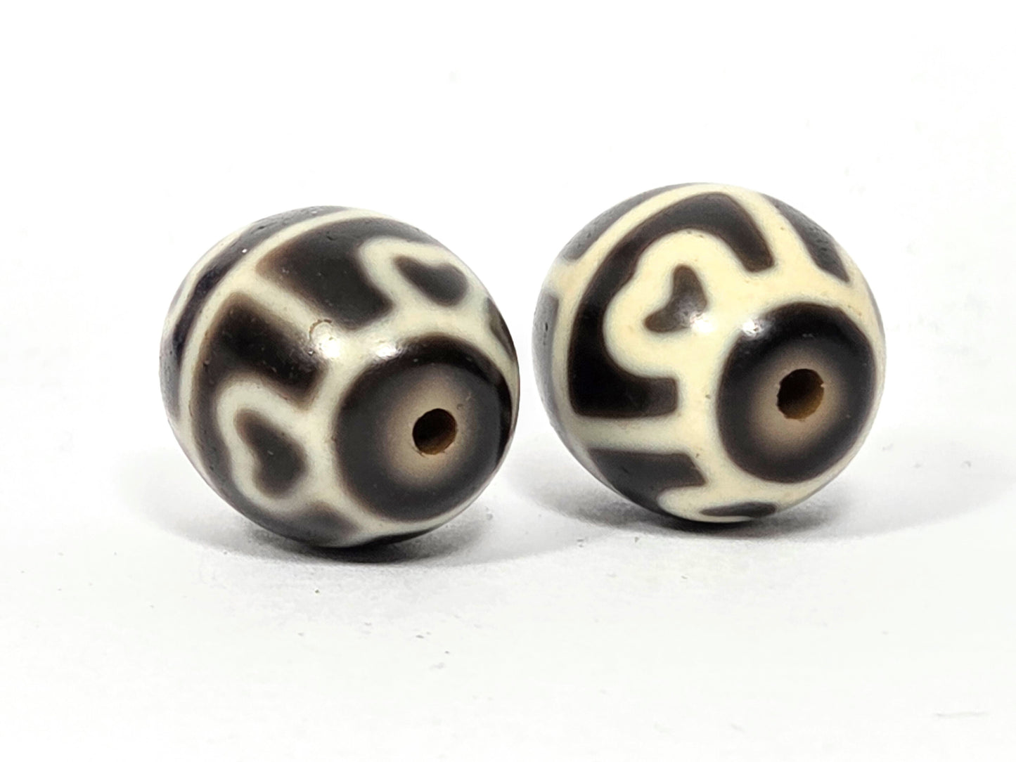 Close up photo showing the drill holes on this pair of six eye lotus antique tibetan dzi beads