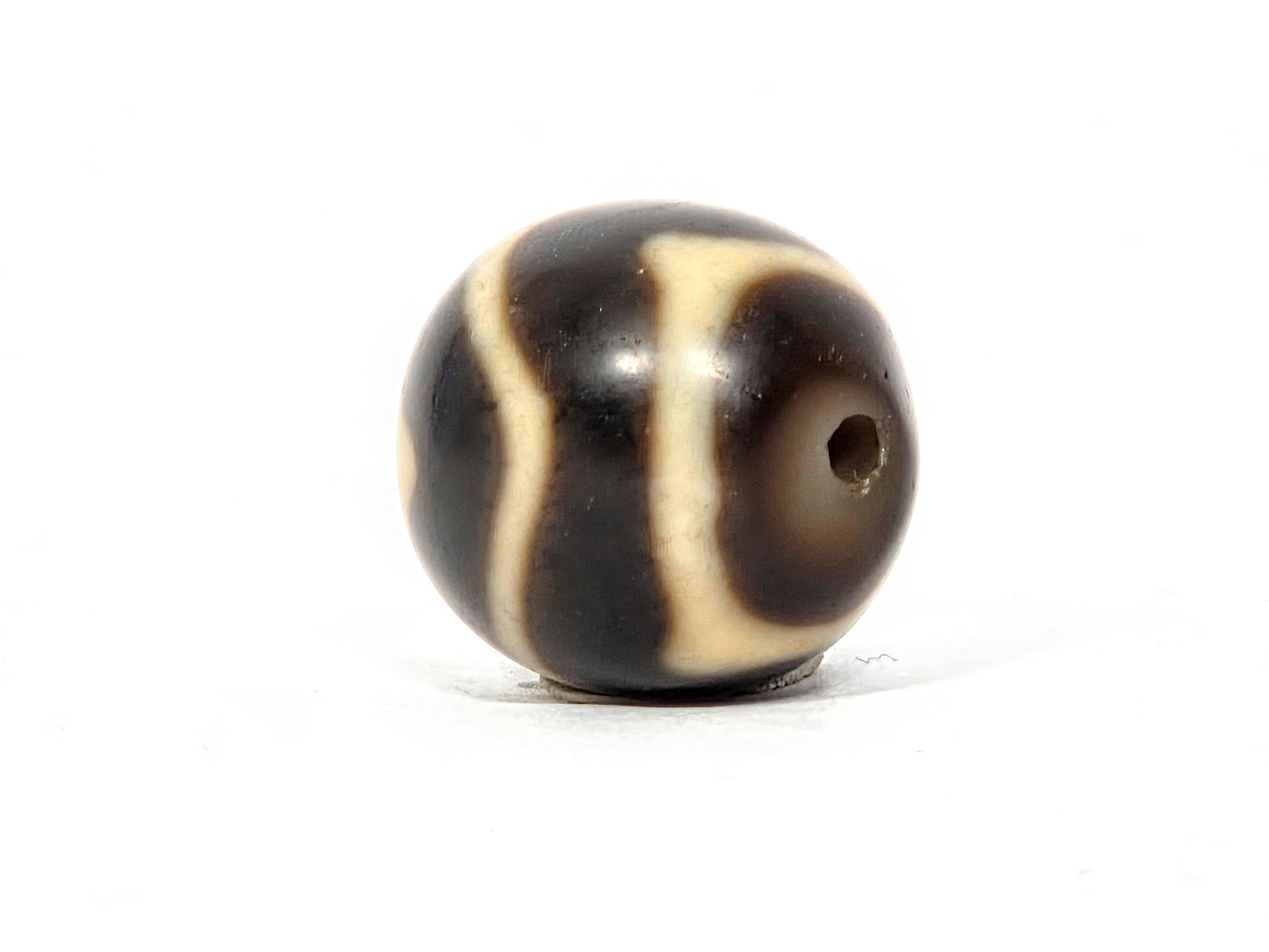 At-111325-WTT antique round wave tiger tooth dzi, drill end view, chocolate-brown end cap, hole centred, unretouched