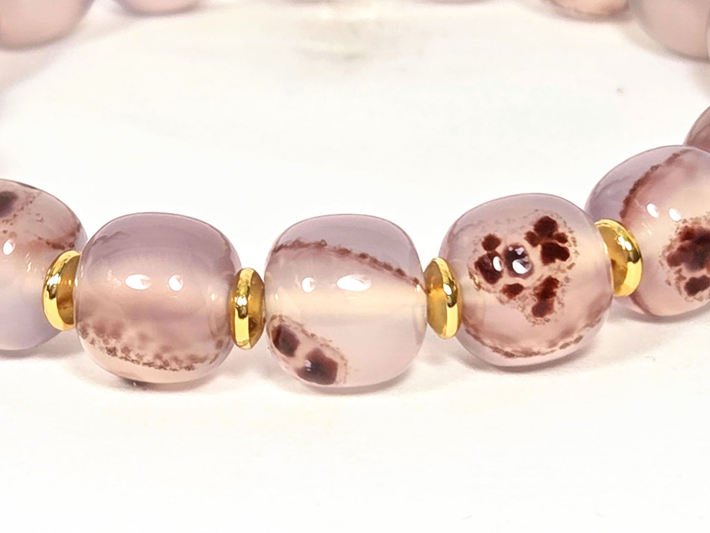 N-030526-CB2 macro, cross-form cinnabar cluster mass in dusty mauve-rose agate, gold spacers flanking, unretouched