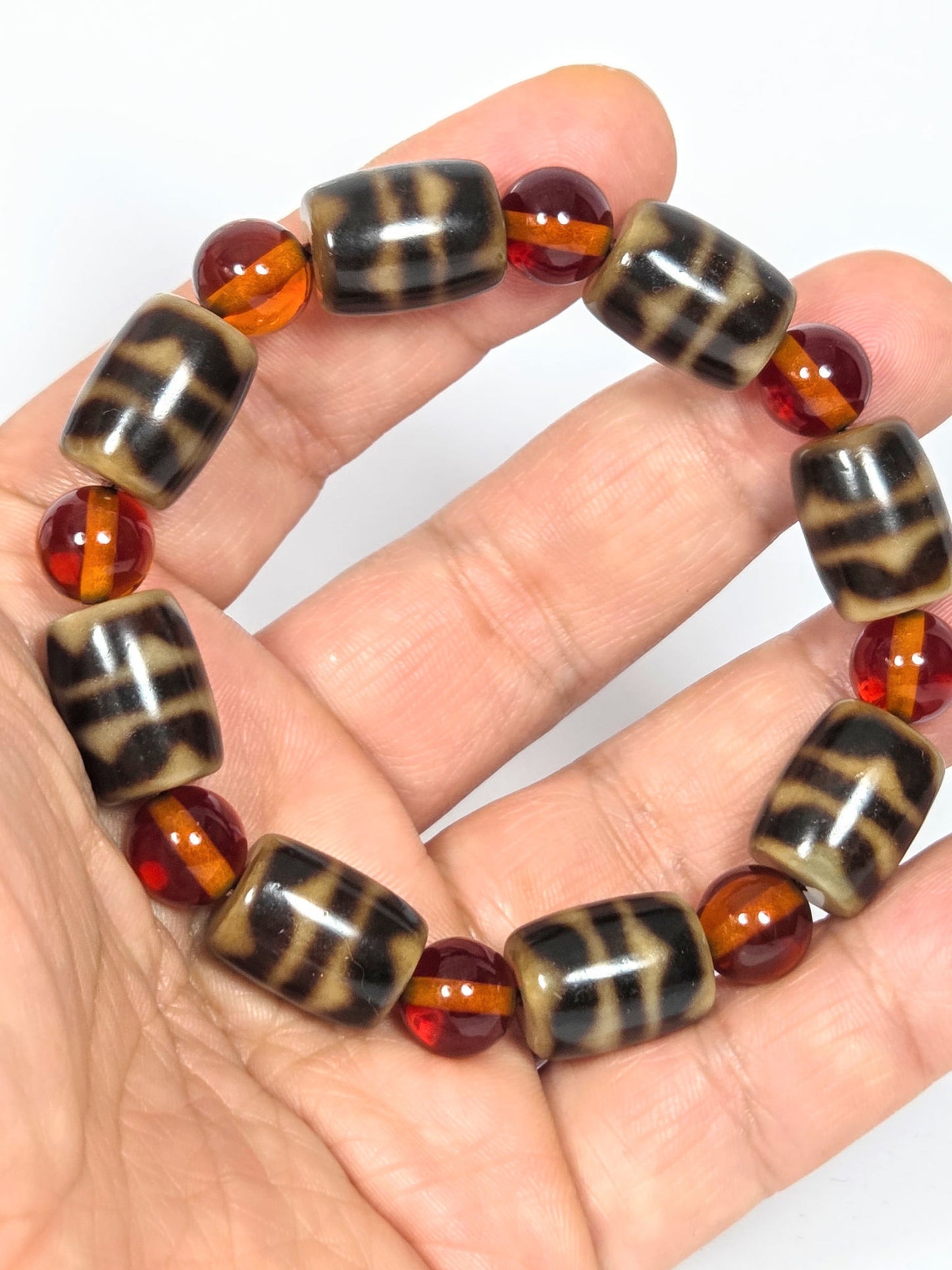 N-021626-DWA double wave dzi & amber bracelet on hand, showing scale and alternating bead pattern, unretouched