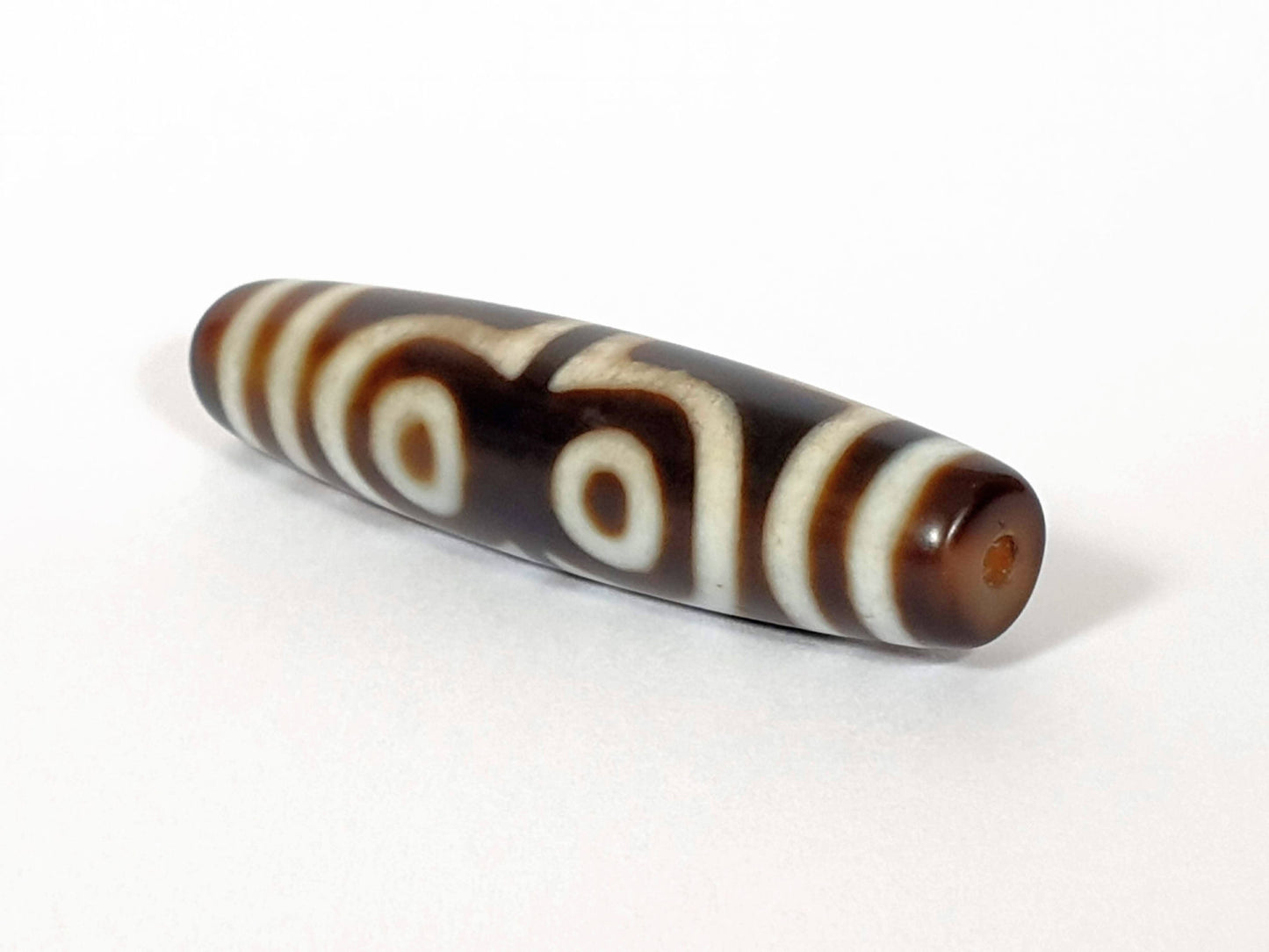 N-062426-4E new four eye dzi 58.5x13.9mm angled view asymmetric taper drill hole end warm brown agate unretouched