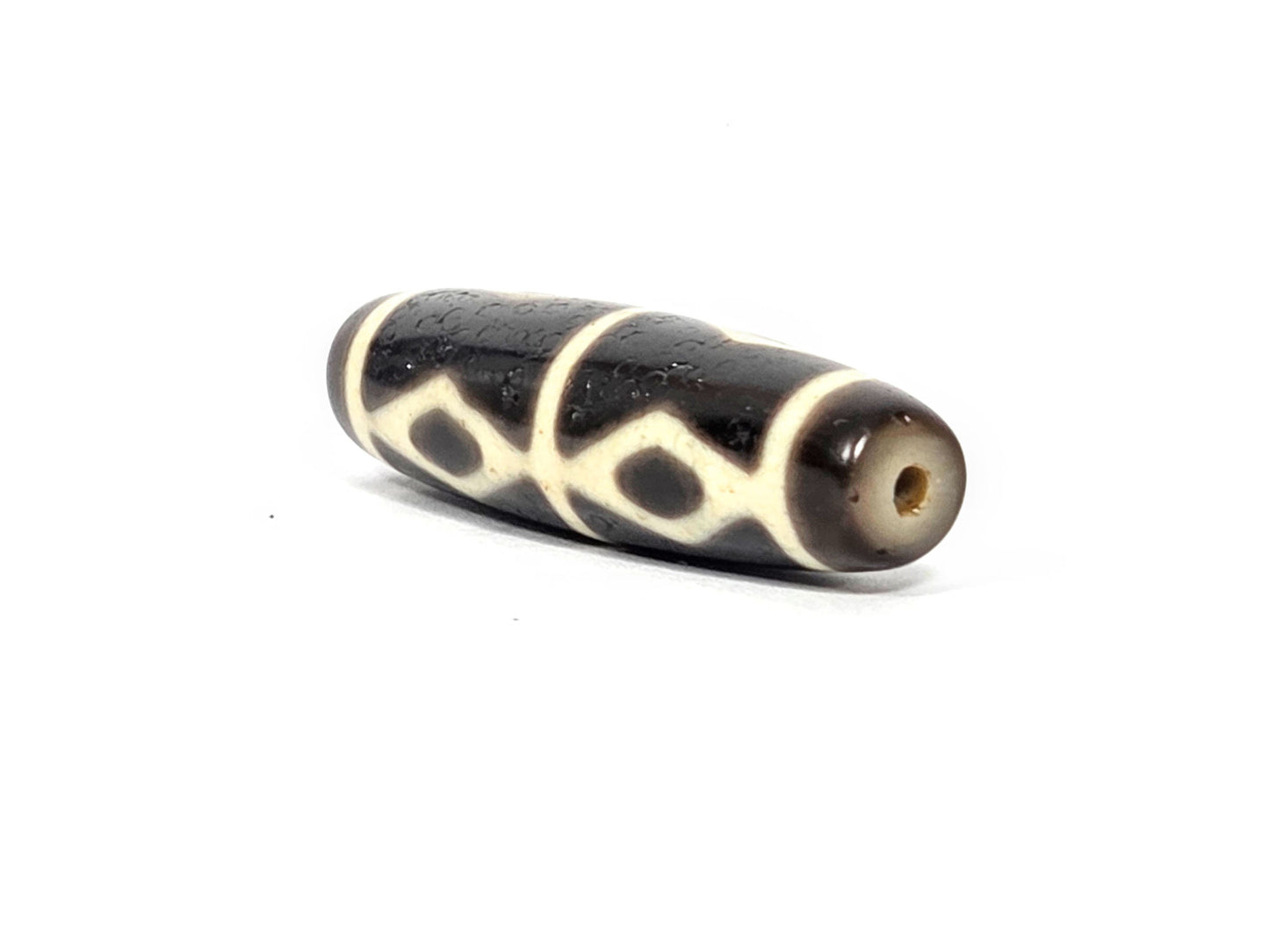 At-072226-6EDS end angle A — warm dark brown end cap, small clean drill opening, diamond motif wrapping, unretouched.