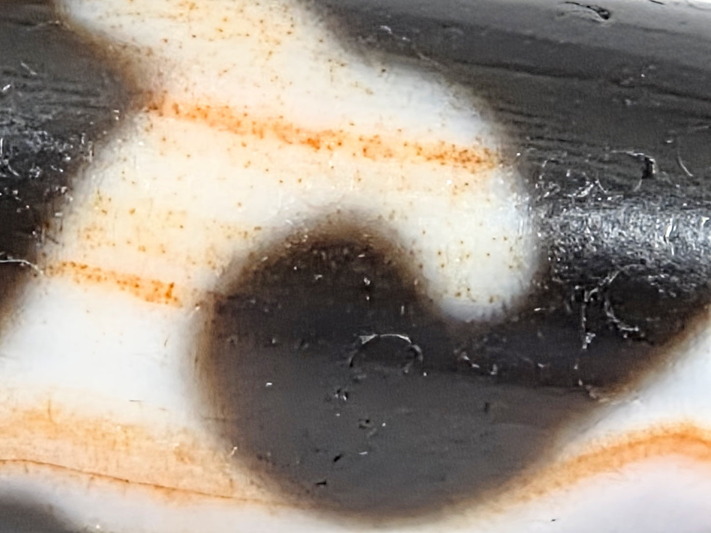 Macro detail of natural cinnabar bloodspot specks surrounding Green Tara motif on antique Tibetan Dzi bead — authentic geological inclusions — unretouched photo — Ancient Dzi Shop