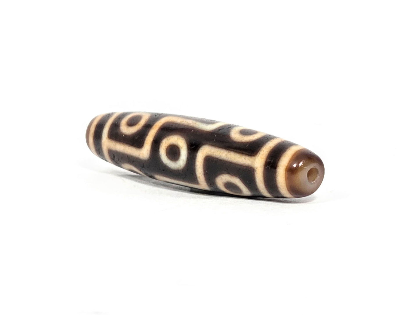 At-071326-9E2 three-quarter end, warm honey-golden cap, small drill hole, slender fusiform taper visible, unretouched