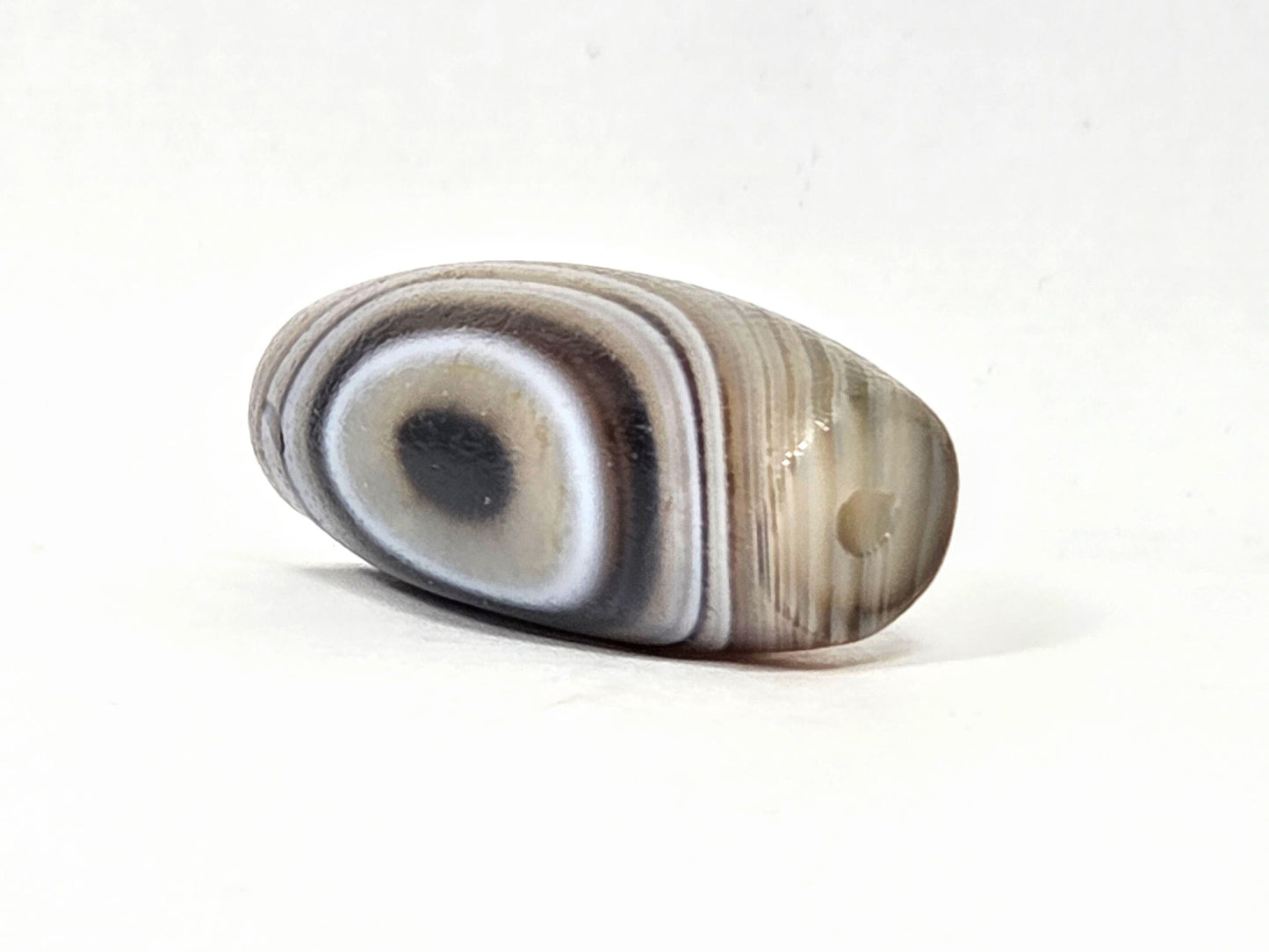 N-N-062126-1E2 dzi bead, three-quarter angle showing tapered end, unretouched