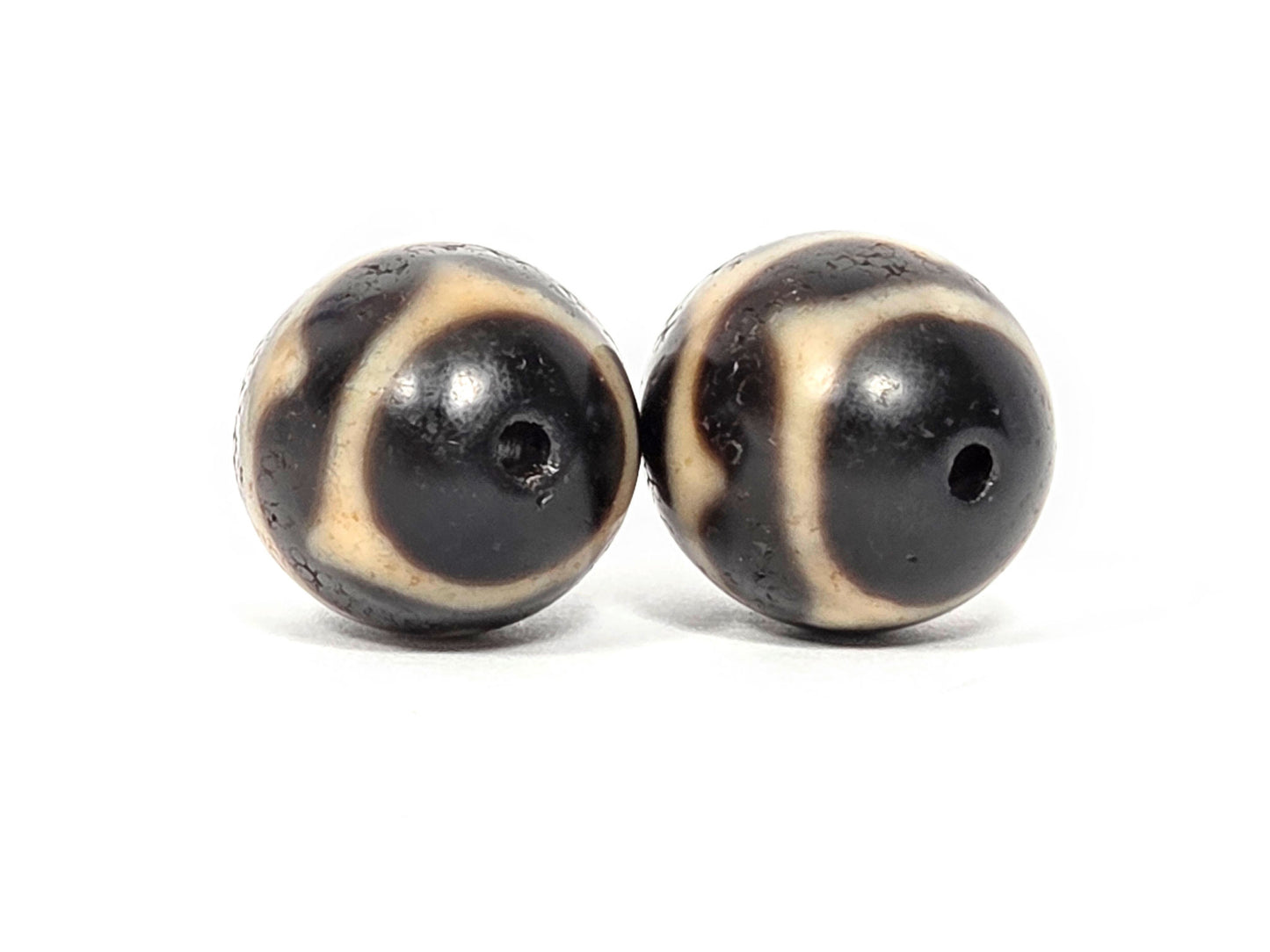 V-060826-DWP2 drill hole end face pair, pitch-black cap, cream wave arc, small centred holes, unretouched