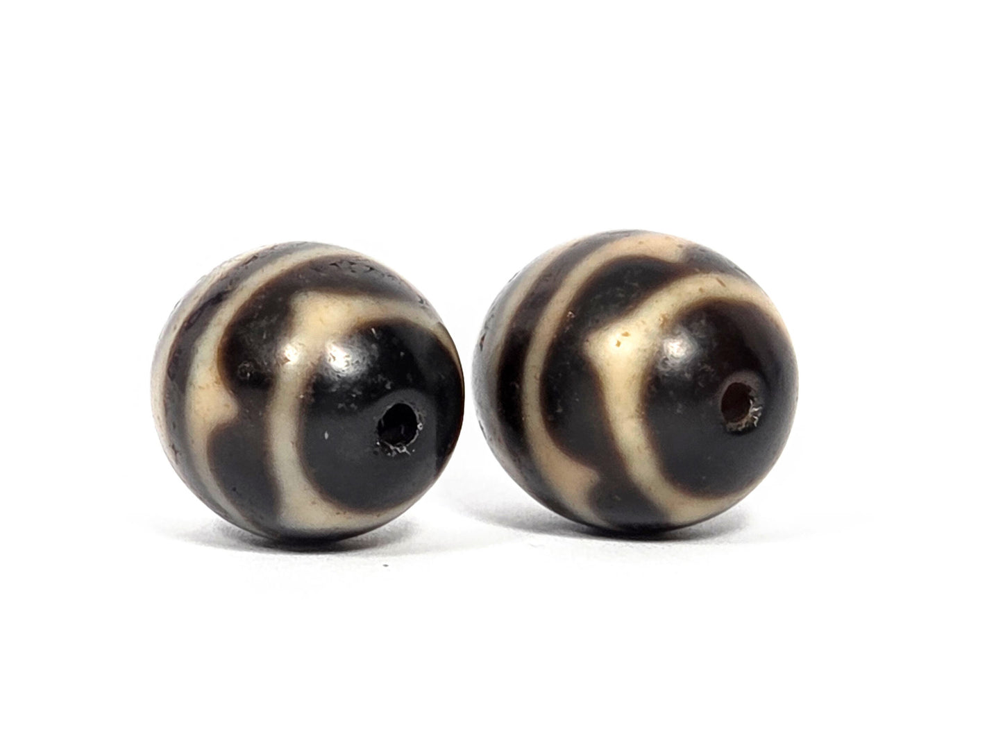 V-071426-DWP3 Double Wave pair drill-end angle A — wave arcs at pole, Bead A deep dark pole, Bead B brown pole, unretouched.