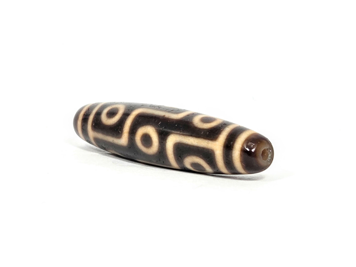 At-070626-9E antique nine eye dzi, angled view drill end B, warm reddish-brown domed end cap, eye network visible, unretouched