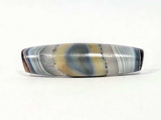 Antique natural dzi bead with naturally formed eye pattern in grey cream and slate blue banding, no etching or artificial treatment, surface patina from age and handling, unretouched photo by Ancient Dzi Shop