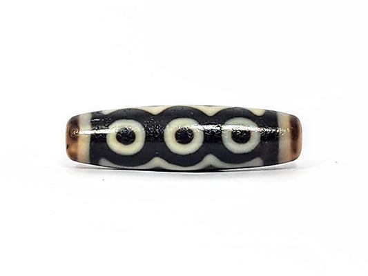 Antique Tibetan five-eye dzi bead, deep near-black agate with five bold cream eye motifs linked by wave band connector, warm brown natural agate end caps, surface patina consistent with antique age, unretouched photo by Ancient Dzi Shop