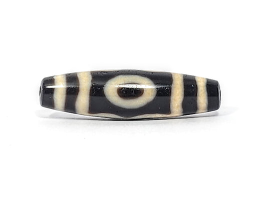 Original authentic ancient Tibetan three-eye dzi bead — near-black agate with bold cream eye motif and stripe pattern, showing heavy surface patina and natural bore holes consistent with extreme age, unretouched photo by Ancient Dzi Shop