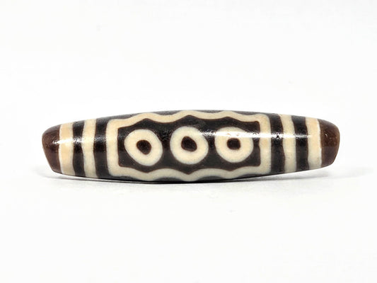 Ancient Tibetan seven-eye dzi bead, dark brown agate, three cream eye motifs with wave dividers, natural surface patina consistent with extreme age, unretouched, Ancient Dzi Shop