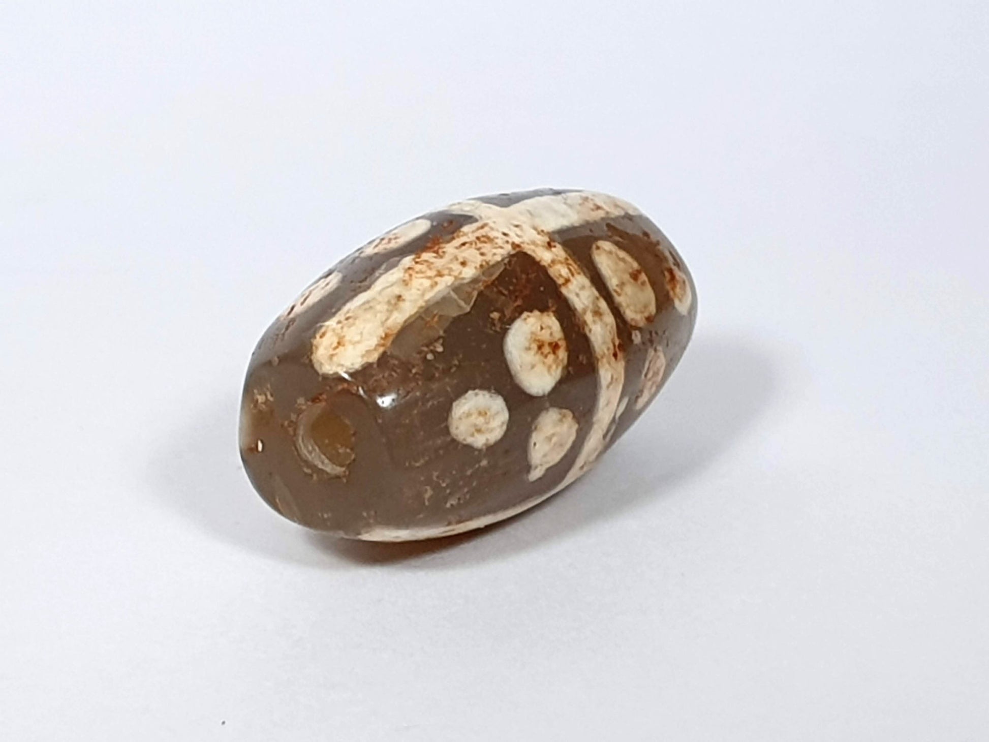 Ac-062426-18S Bead A angled view eighteen star motif medium warm brown agate ancient drill hole visible unretouched