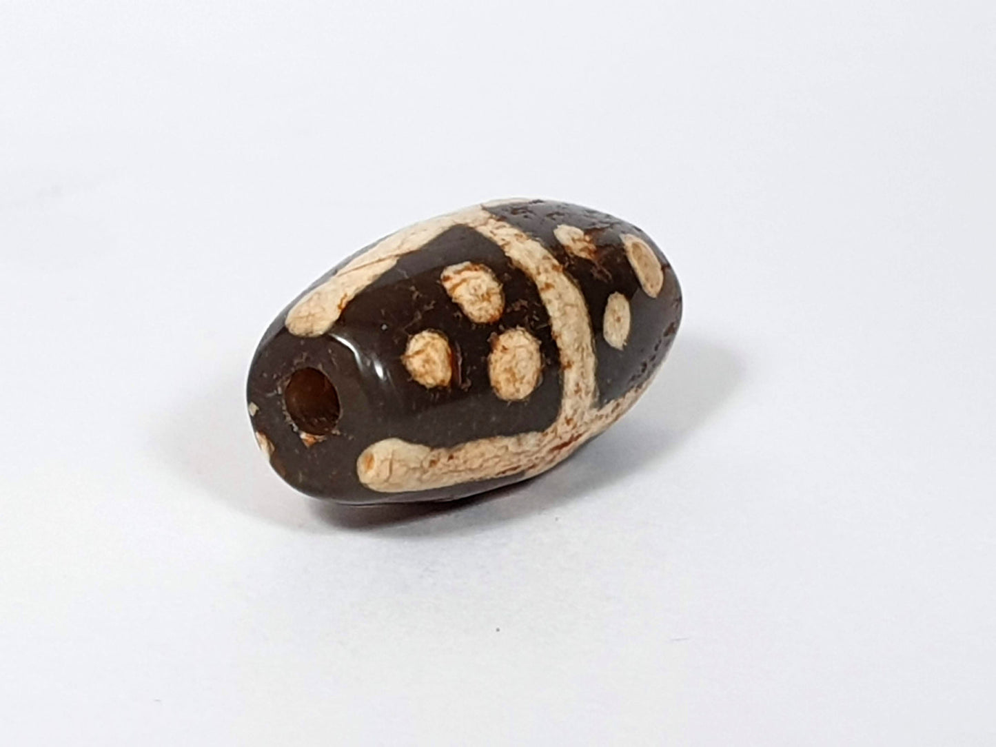 Ac-062426-18S Bead B end-on view large ancient drill hole deep dark warm brown ground unretouched