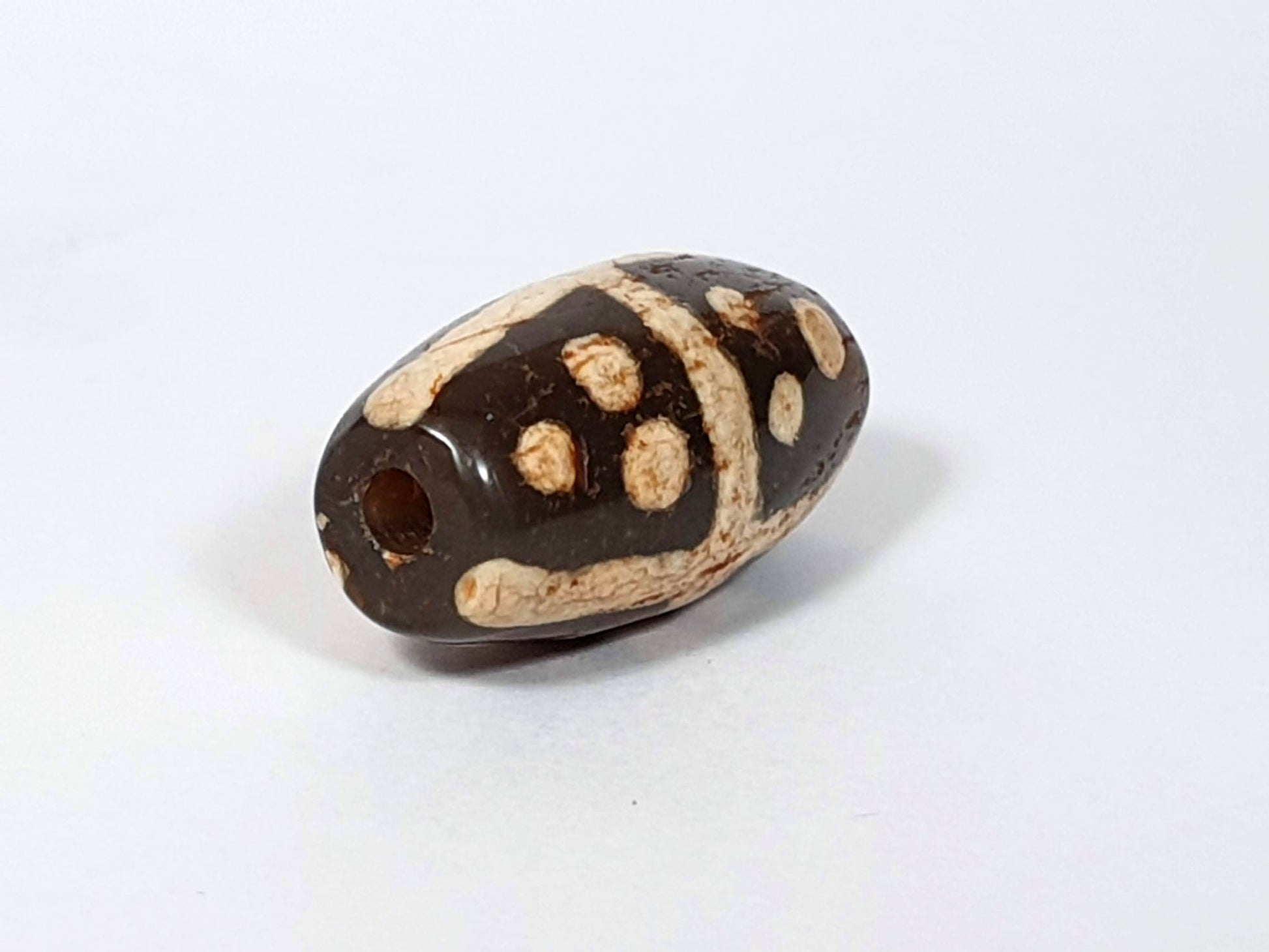 Ac-062426-18S Bead B end-on view large ancient drill hole deep dark warm brown ground unretouched