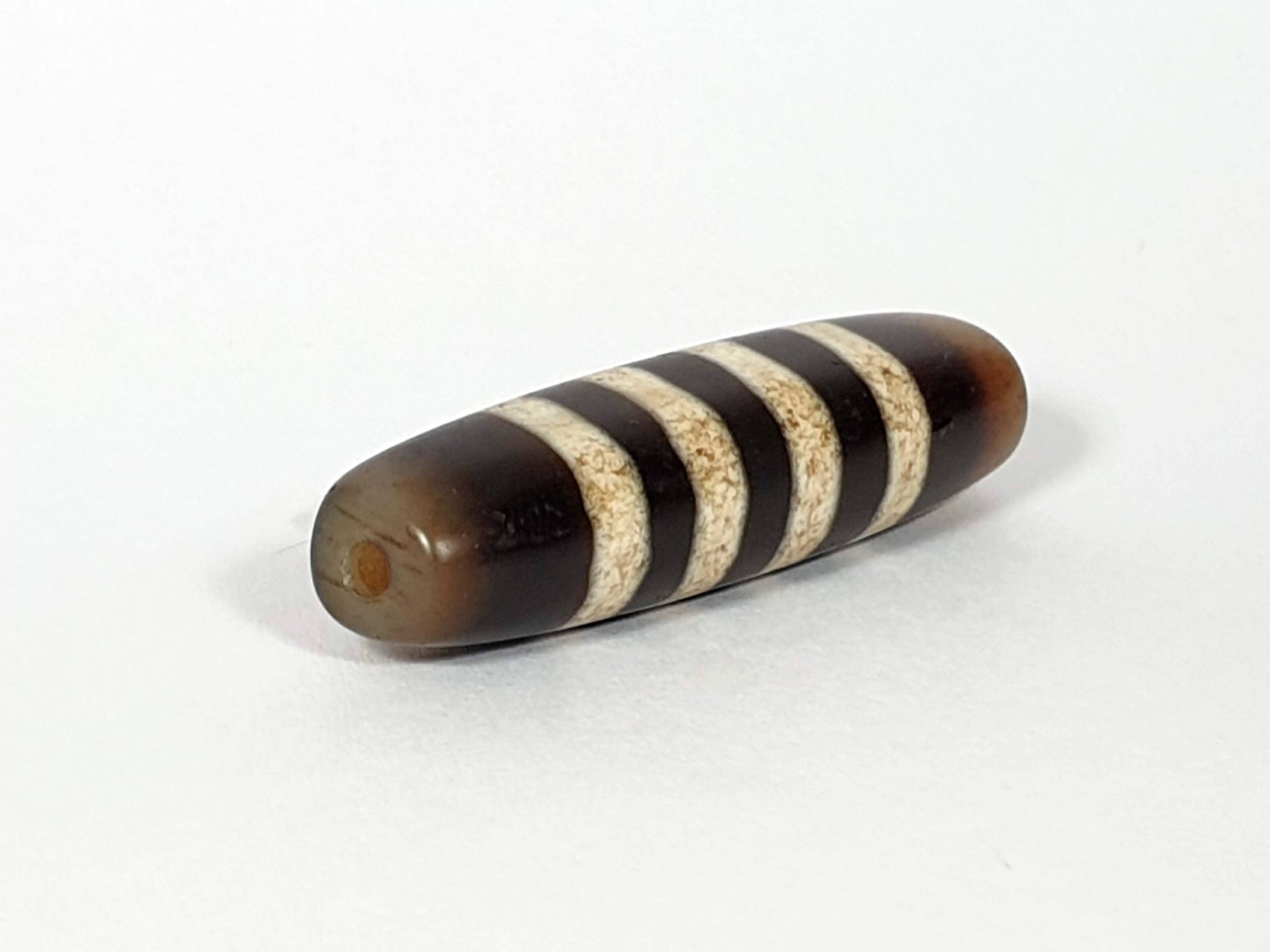 At-061920-7SChung antique seven stripe Chung dzi, left end, intact honey-brown cap, drill hole visible, unretouched