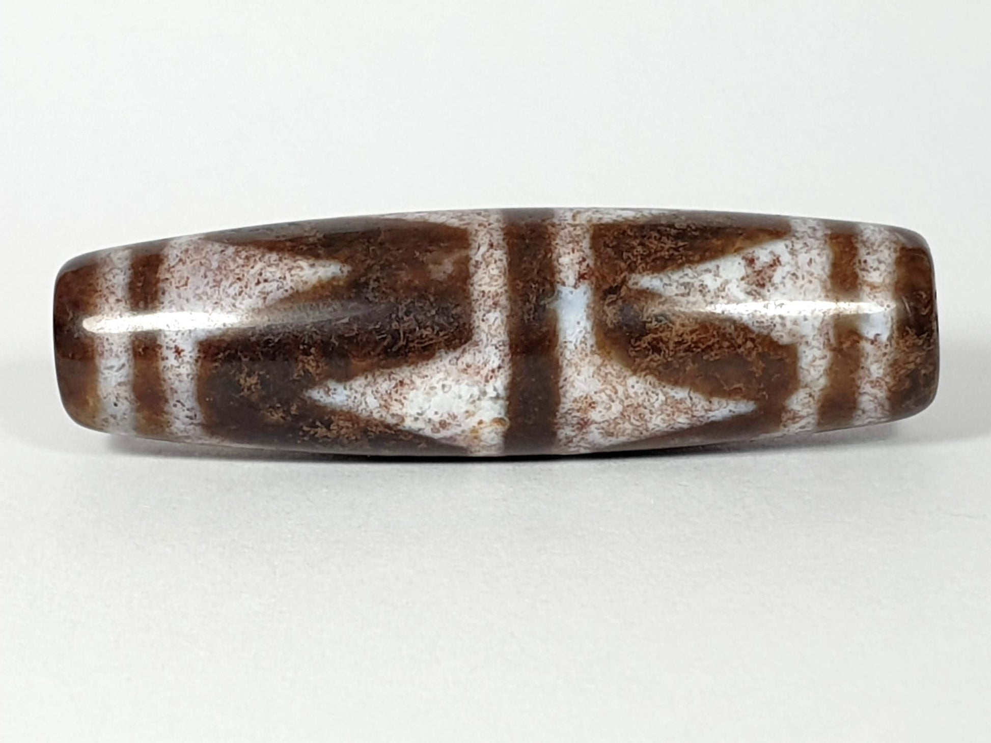 N-062126-DW dzi bead, straight side profile, ivory chevron motif on brown ground, unretouched
