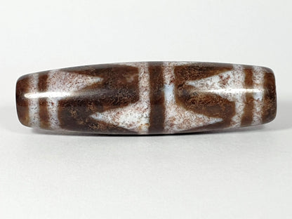 N-062126-DW dzi bead, straight side profile, ivory chevron motif on brown ground, unretouched
