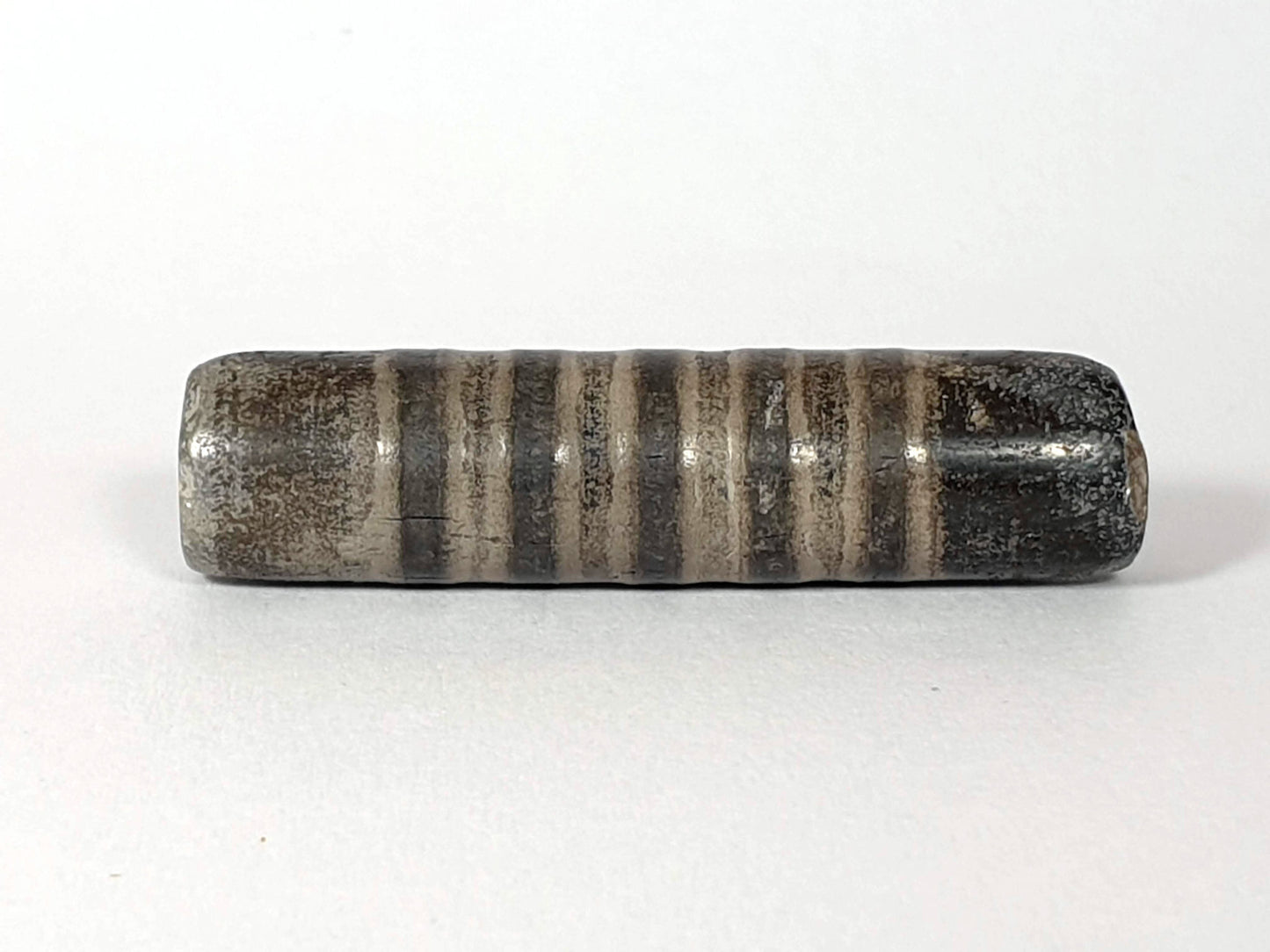Ac-080420-19SChung, Bead A lateral, 19 narrow stripe bands on dark grey-brown ground, matte weathered surface, unretouched