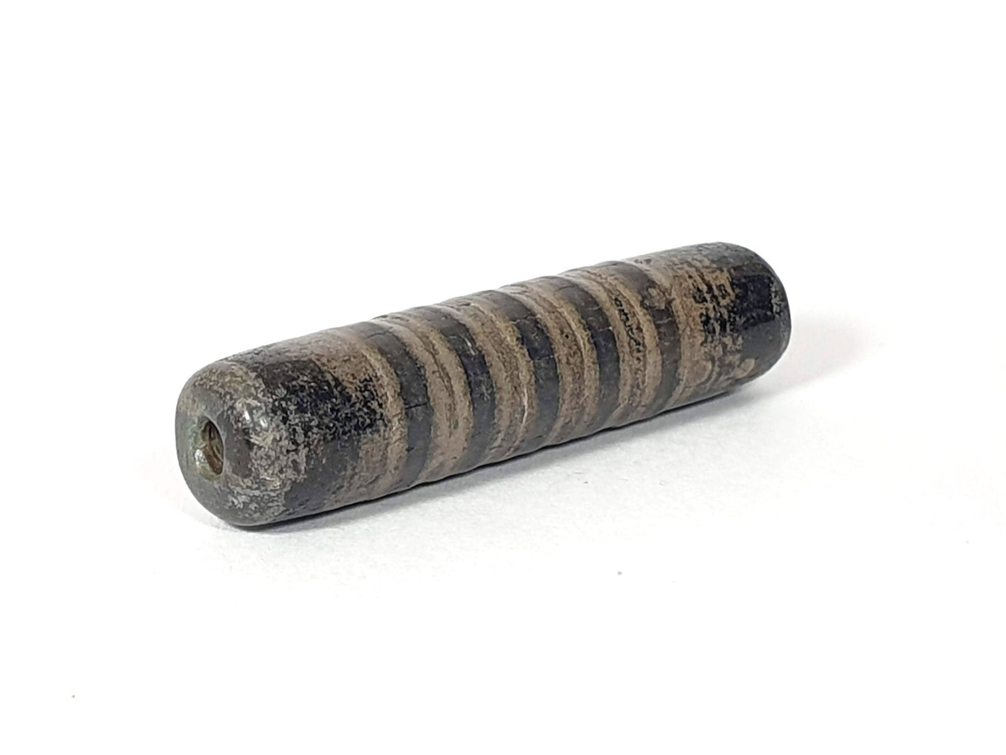 Ac-080420-19SChung, Bead B left end drill hole, encrusted end face, narrow stripe bands visible on cylindrical body, unretouched