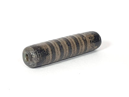 Ac-080420-19SChung, Bead B left end drill hole, encrusted end face, narrow stripe bands visible on cylindrical body, unretouched