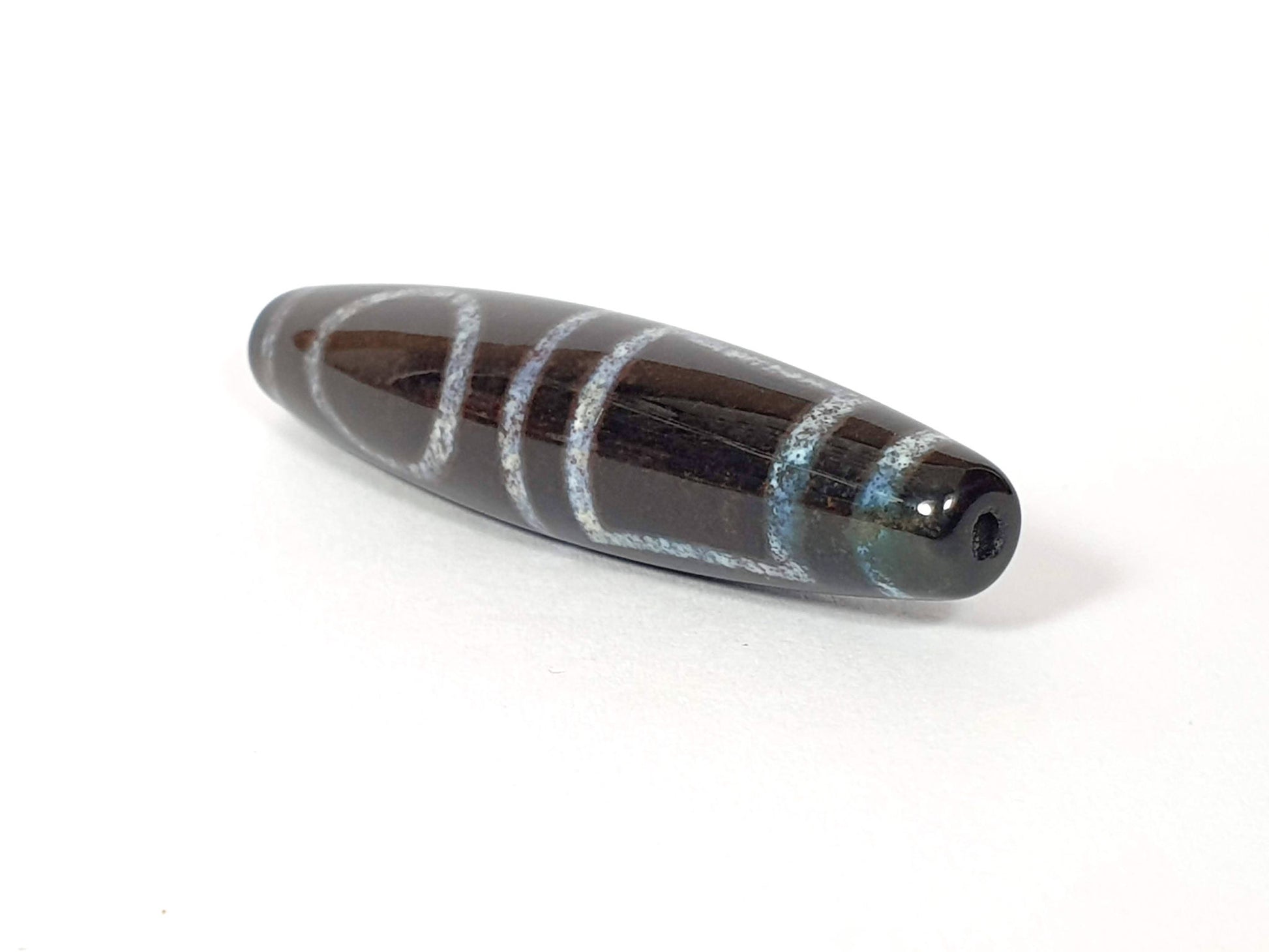 N-062126-HE dzi bead, three-quarter angle showing drilled end, unretouched