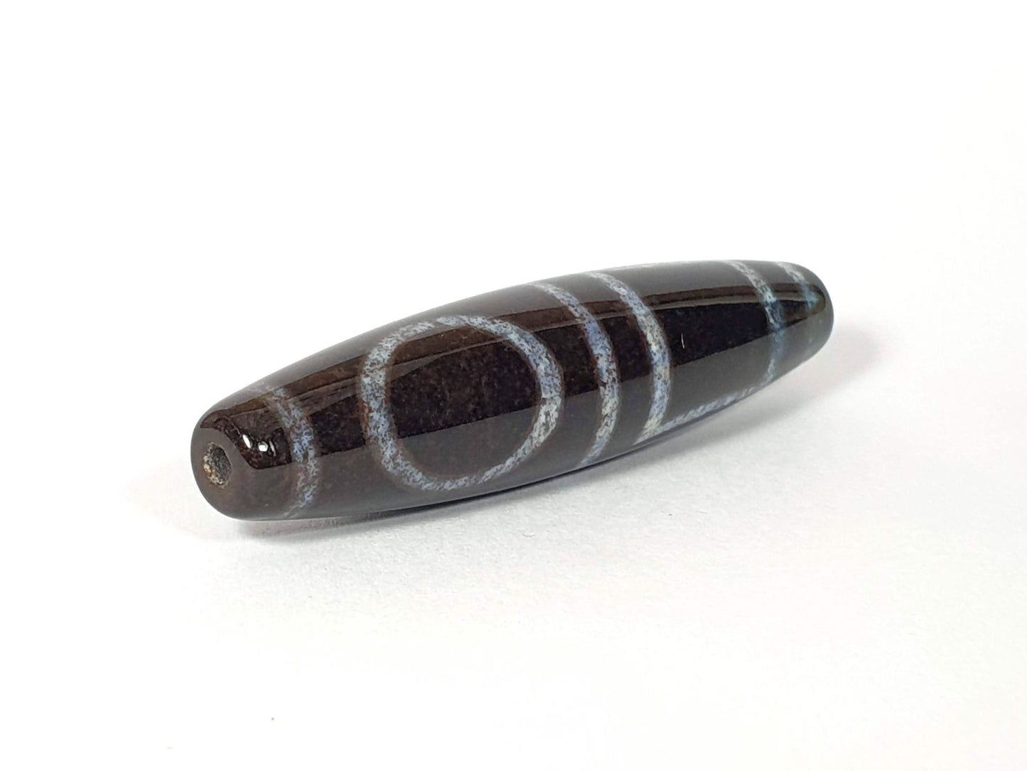 N-062126-HE dzi bead, angled view of opposite drilled end, full motif visible, unretouched