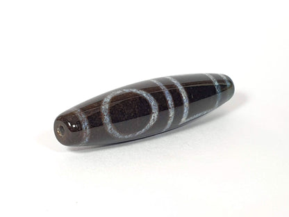 N-062126-HE dzi bead, angled view of opposite drilled end, full motif visible, unretouched