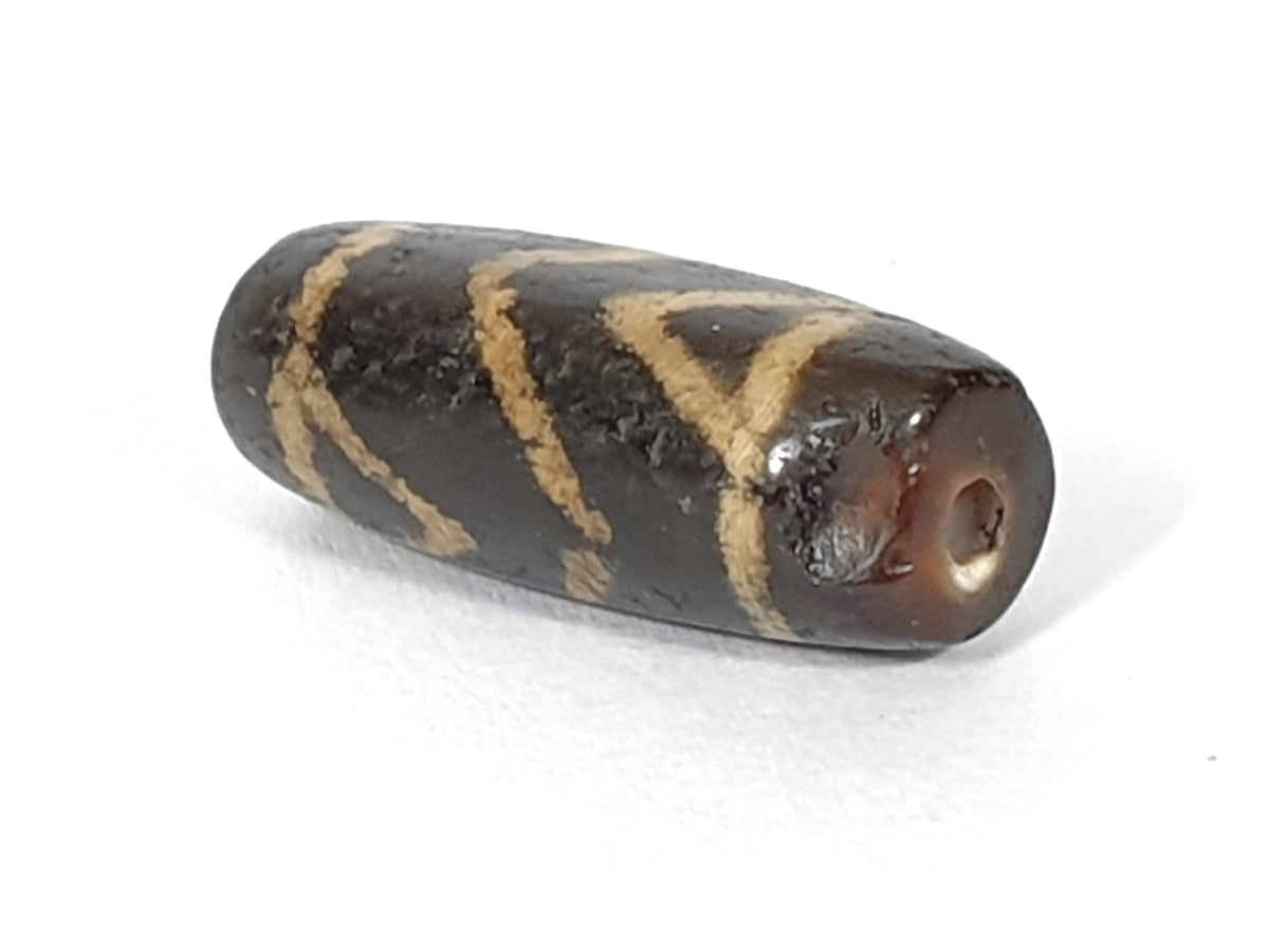 Ancient carnelian dzi bead, tiger tooth motif, dark brown agate, etched cream stripes, visible drill hole, aged patina