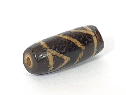 Ancient carnelian dzi bead, tiger tooth motif, dark brown etched agate, cream geometric pattern, visible drill hole, aged patina