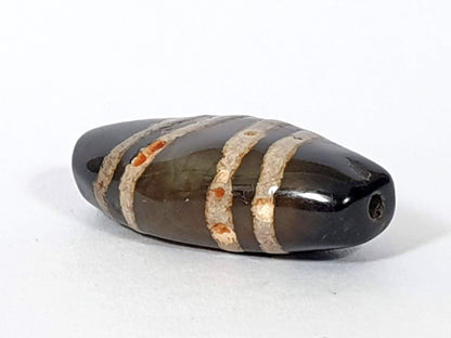 Ac-111720-7SOS, right end 3/4 view, pitch-black tip, drill hole, cinnabar bloodspot clusters in stripe bands, unretouched
