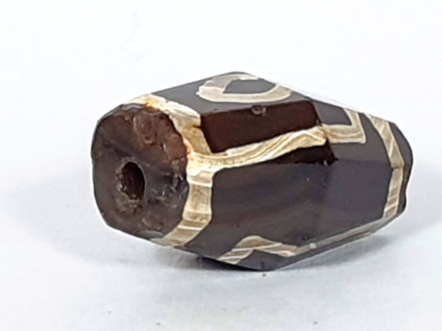 At-120120-2E7, opposite octagonal end face, ancient drilled hole, reddish oxidation, cream motif wrapping, unretouched