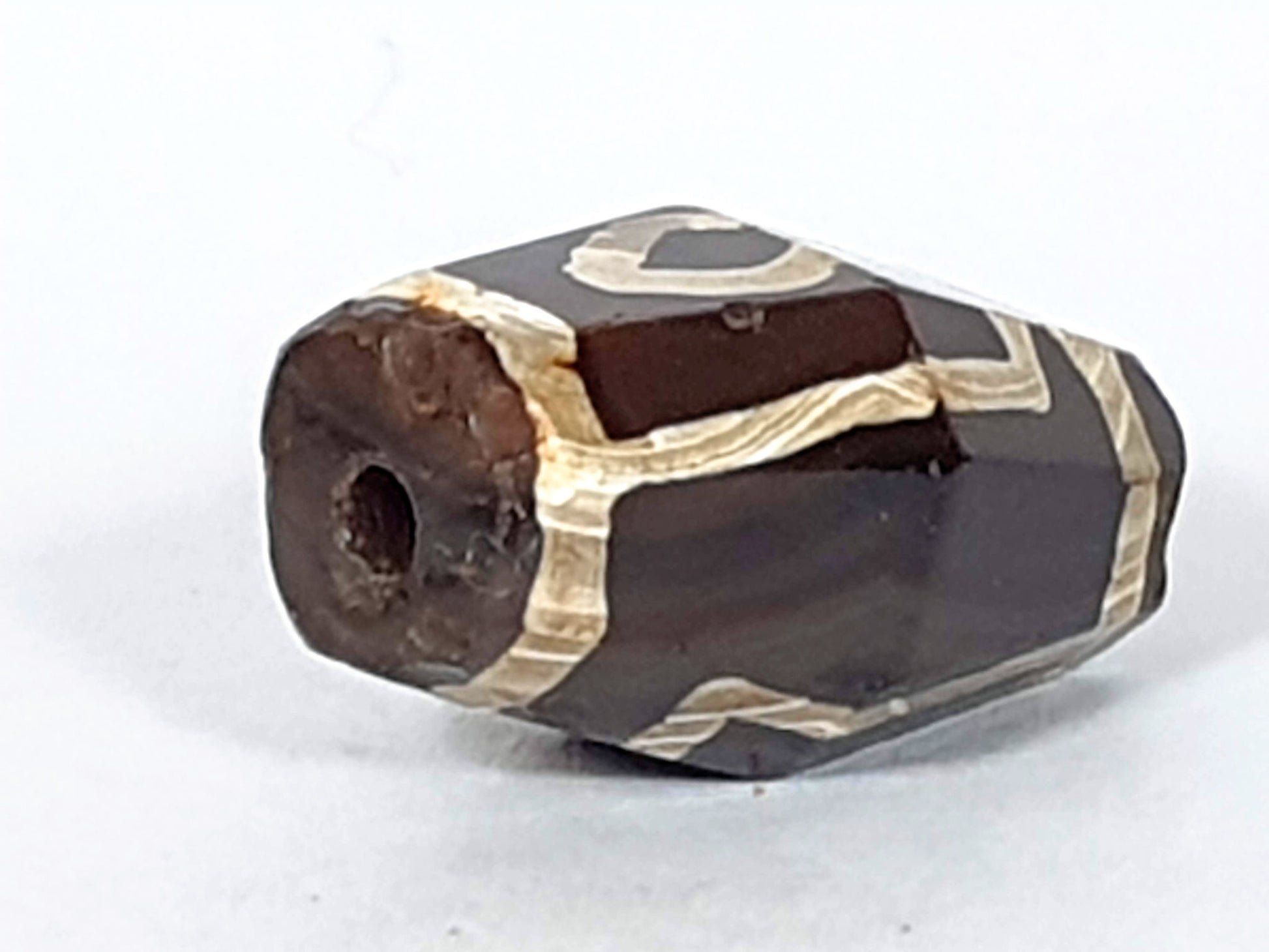 At-120120-2E7, opposite octagonal end face, ancient drilled hole, reddish oxidation, cream motif wrapping, unretouched