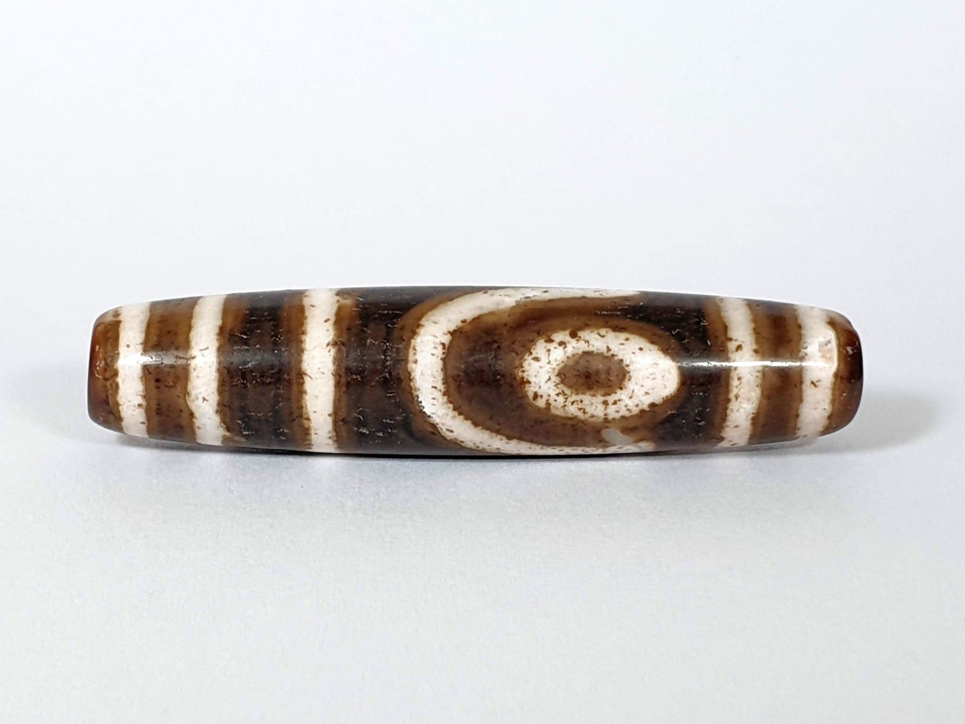 Qing Dynasty two eye dzi — front face, bold spiral eye centred on dark brown ground, bracket bars flanking, At-0426-2EQ