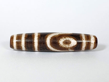 Qing Dynasty two eye dzi — front face, bold spiral eye centred on dark brown ground, bracket bars flanking, At-0426-2EQ
