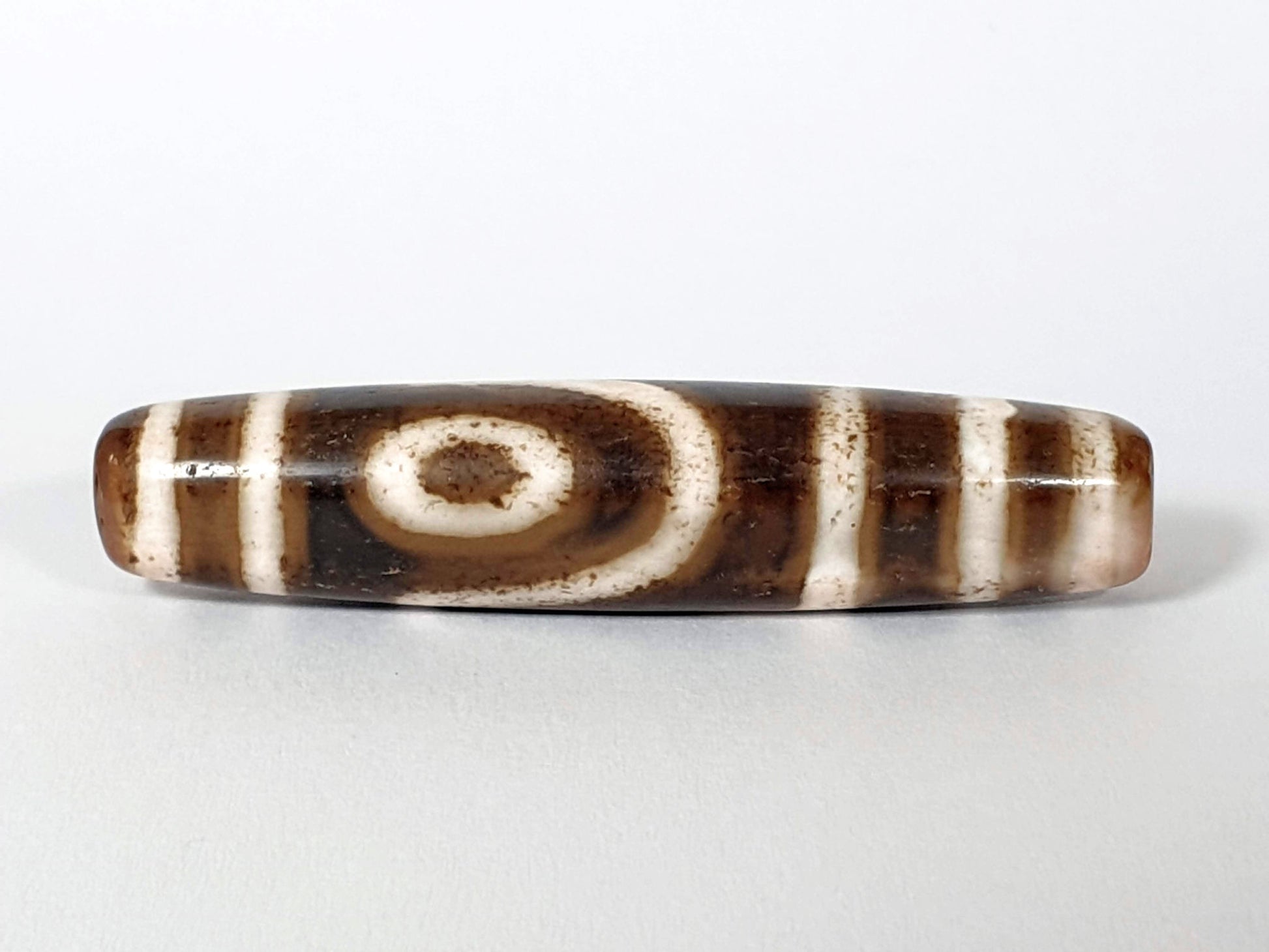 	Qing Dynasty two eye dzi — third face, second spiral eye on warm brown ground with pink-blush end, bracket bars, At-0426-2EQ