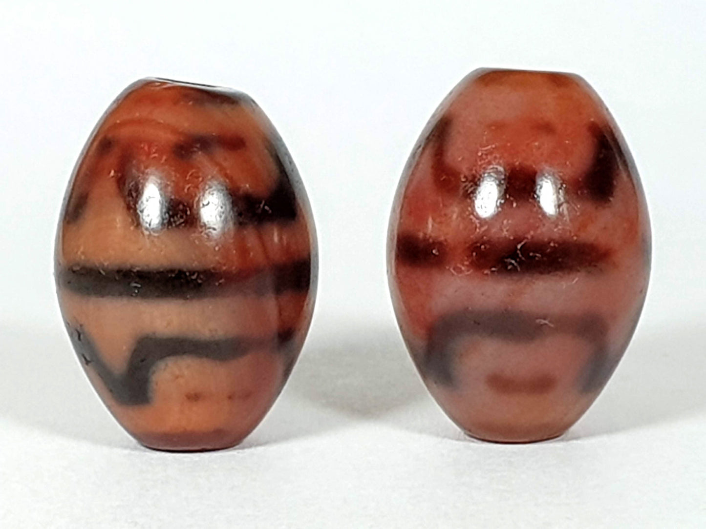 At-062926-TTBS pair front face, Bead A high-contrast black banding left, Bead B softer brown banding right, unretouched