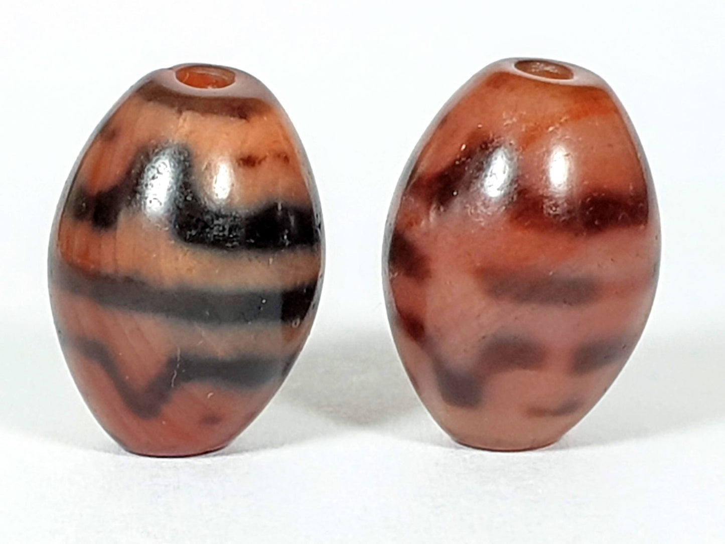 At-062926-TTBS pair top-down, drill holes visible, multifaceted crown profile both beads, warm terracotta agate, unretouched