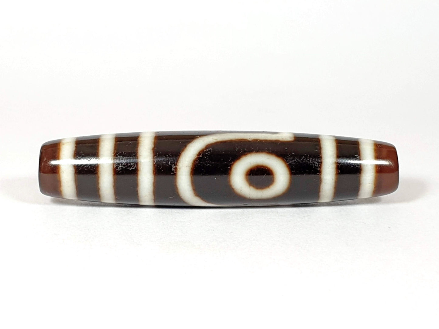 V-070226-2E2 vintage two eye dzi bead, front view, brown to black ground, 54.5×11.9mm, unretouched.