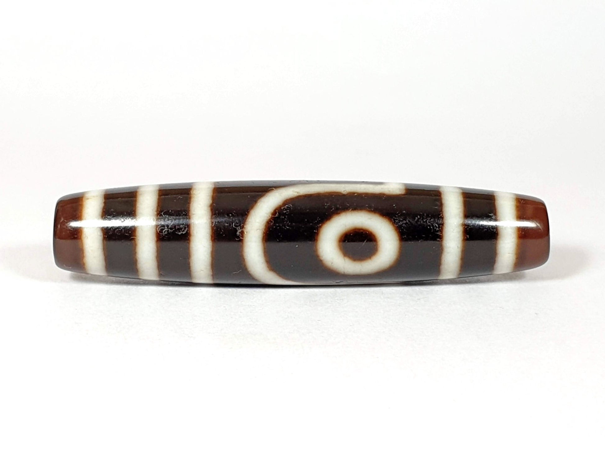 V-070226-2E2 vintage two eye dzi bead, front view, brown to black ground, 54.5×11.9mm, unretouched.
