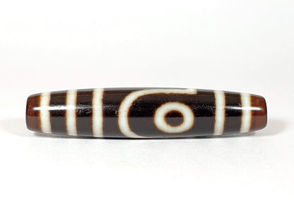 V-070226-2E2 vintage two eye dzi bead, front view, brown to black ground, 54.5×11.9mm, unretouched.