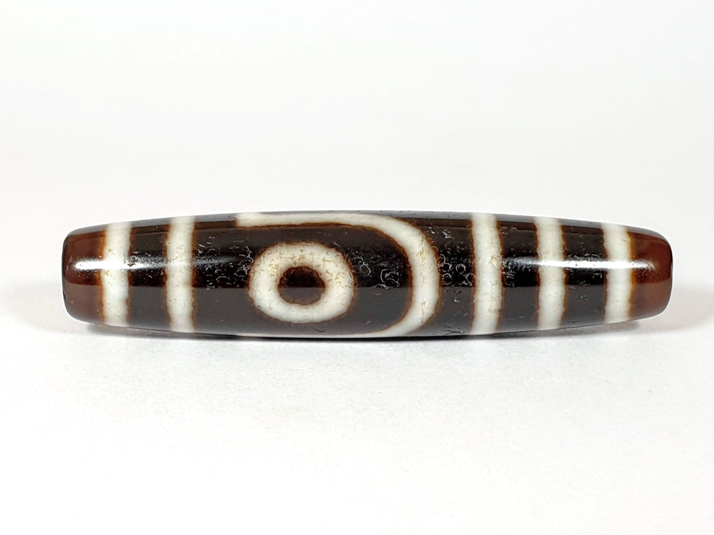 V-070226-2E2 dzi bead, front view, cream eye ring on brown-black ground, unretouched photo.