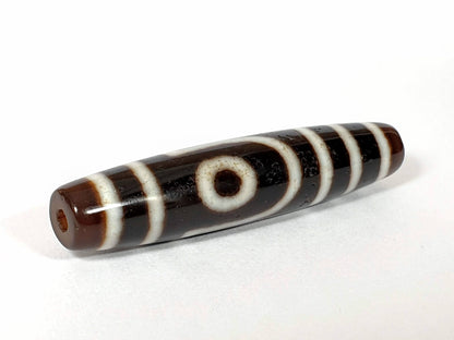 V-070226-2E2 dzi bead, diagonal view showing full stripe pattern, brown-black agate, unretouched.
