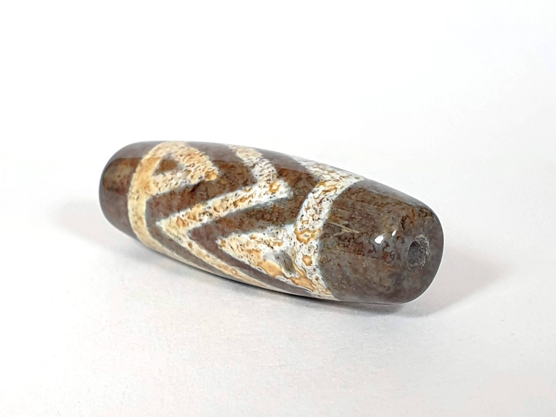 N-062426-3TSBS Bead A three stripe tiger dzi angled view honey-gold chevron motif dark brown ground unretouched