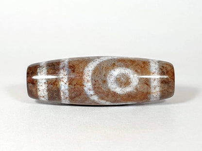 N-062126-2E dzi bead, straight side profile, ring-eye motif on tan ground, unretouched