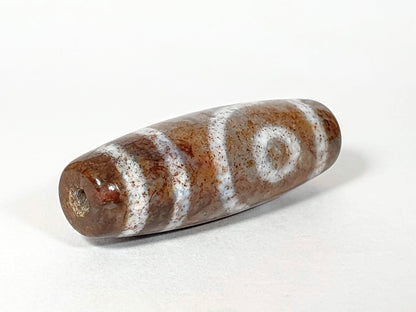 N-062126-2E dzi bead, angled view of drilled end with mineral deposit, unretouched