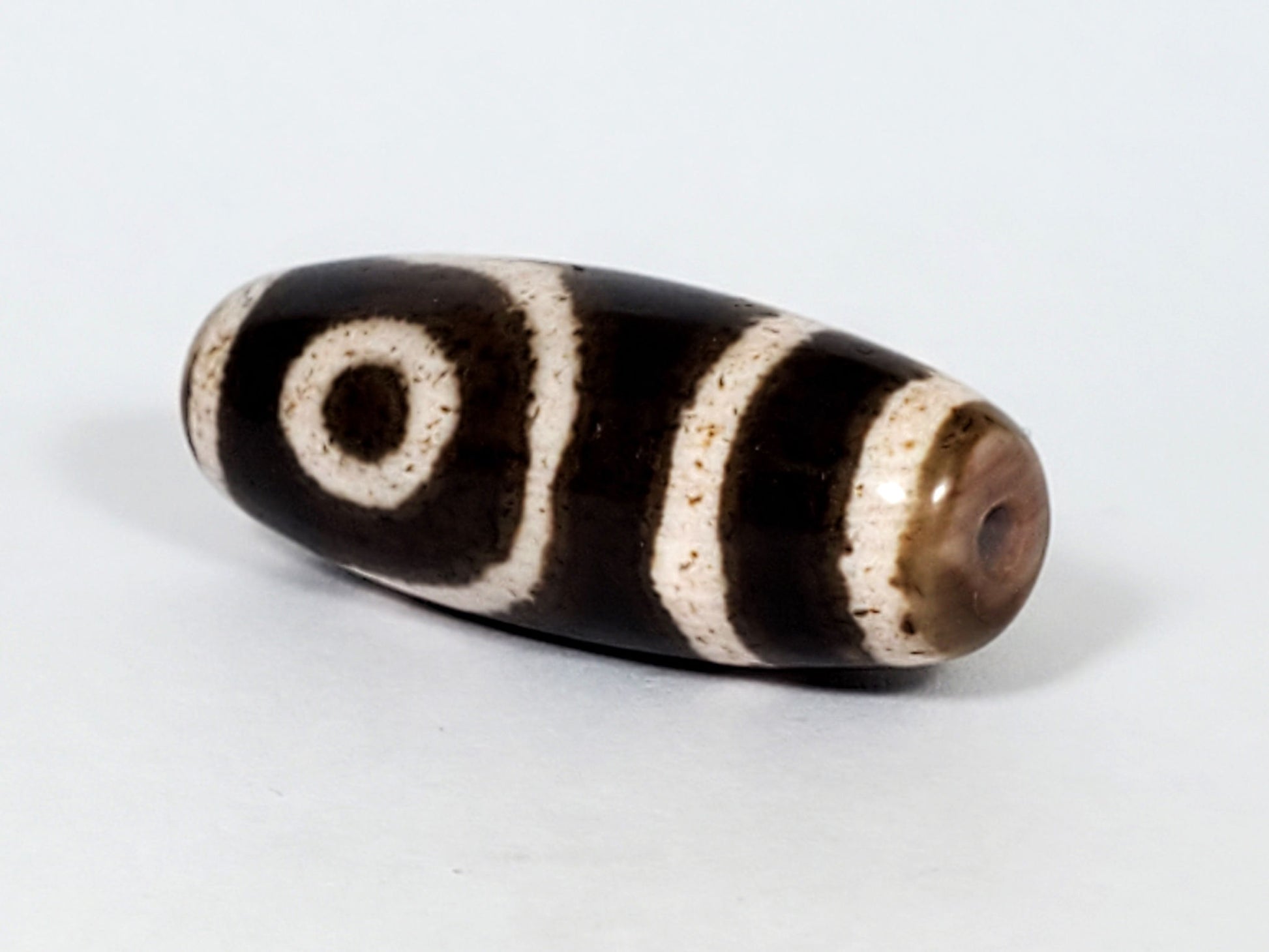 Qing Dynasty two eye dzi — angled opposite end, drill hole at dark brown rounded left tip, spiral eye on body, At-0426-2EQ2